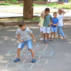 4 Kinder die das Hüpfspiel Himmel und Hölle spielen